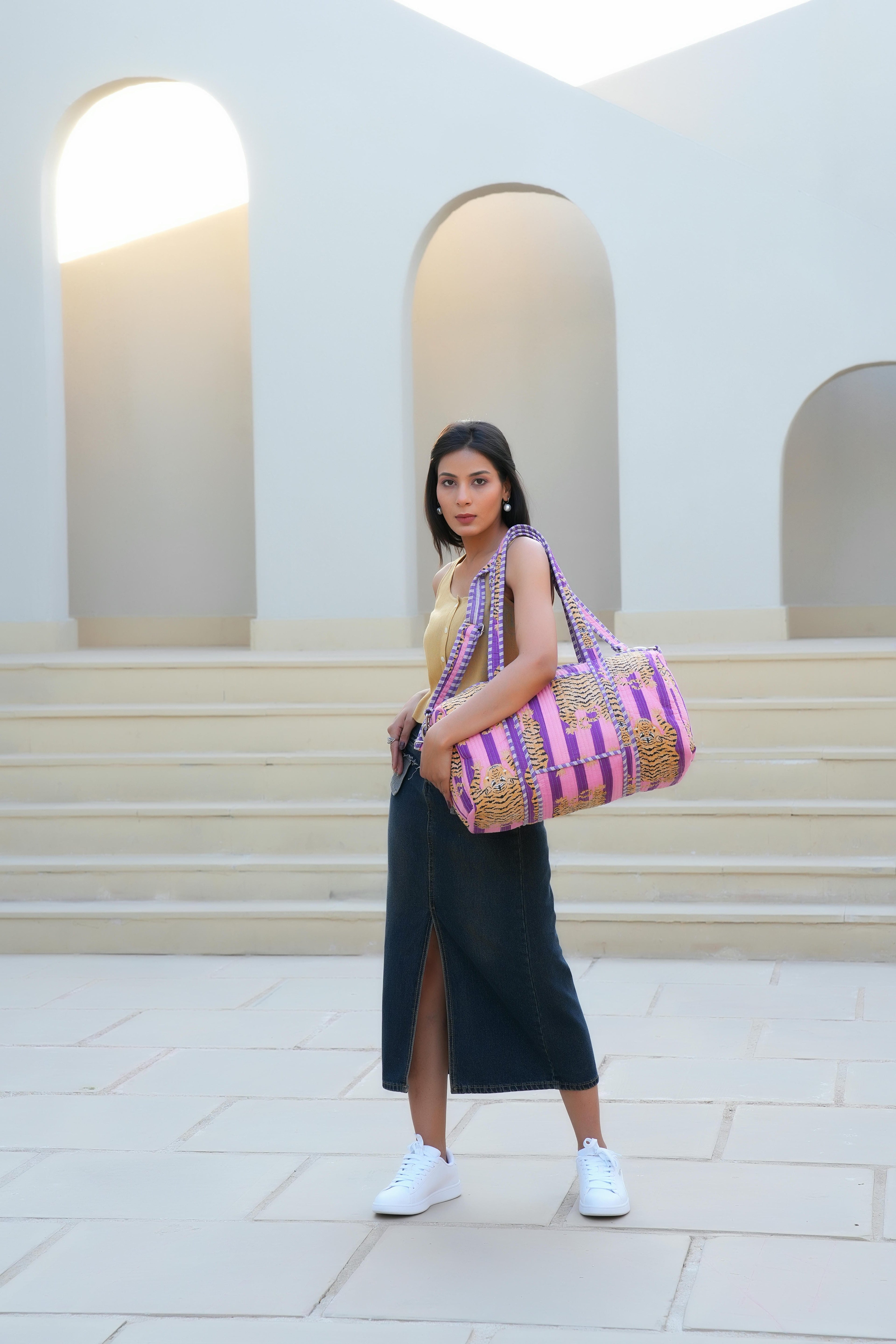 Model carrying The Tibetan Tiger Weekender by the top handles, walking into a hotel lobby