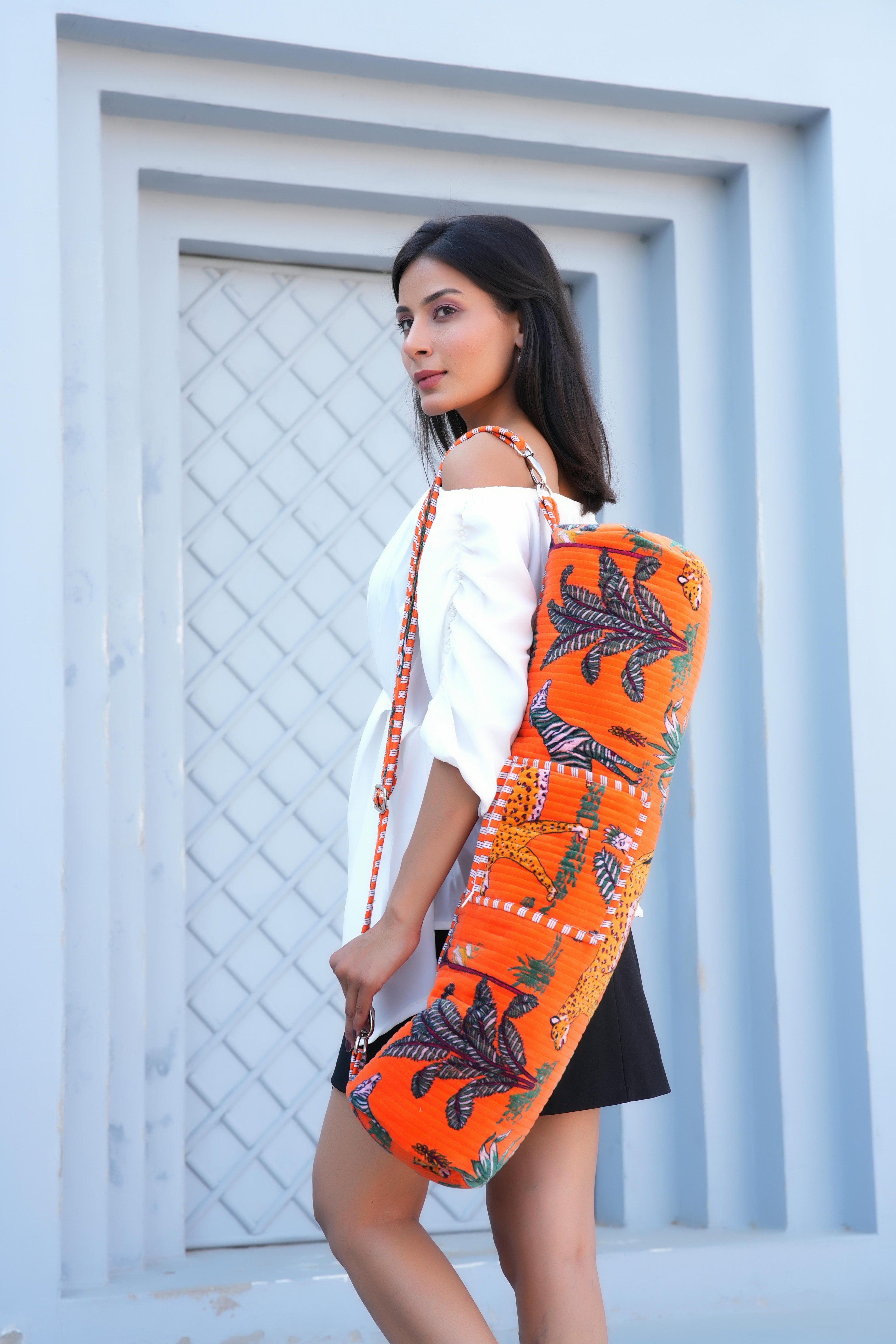 Model carrying The Jungle Velvet Yoga Bag over the shoulder with rolled yoga mat inside, walking to a studio