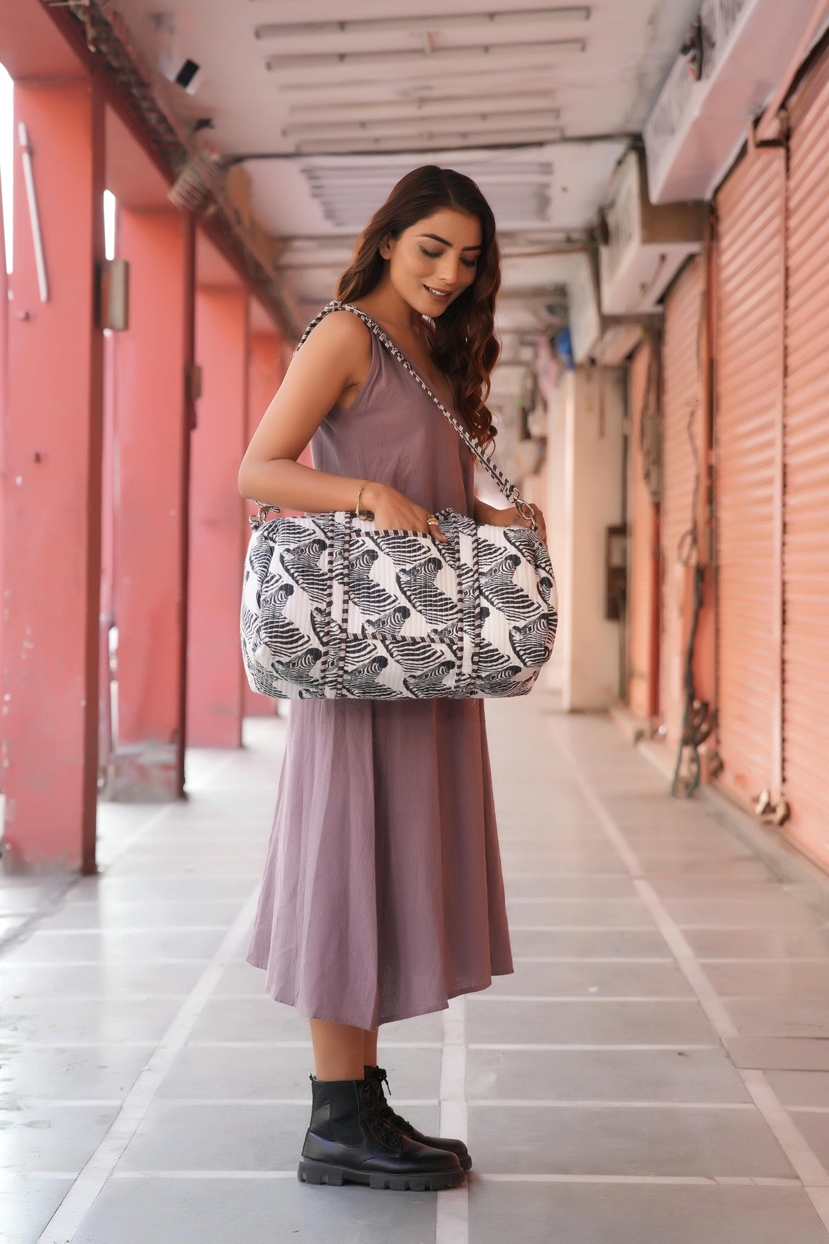 The Zebra Weekender worn on the shoulder by its long strap, side view: handmade cotton weekender, ethically crafted in Rajasthan.