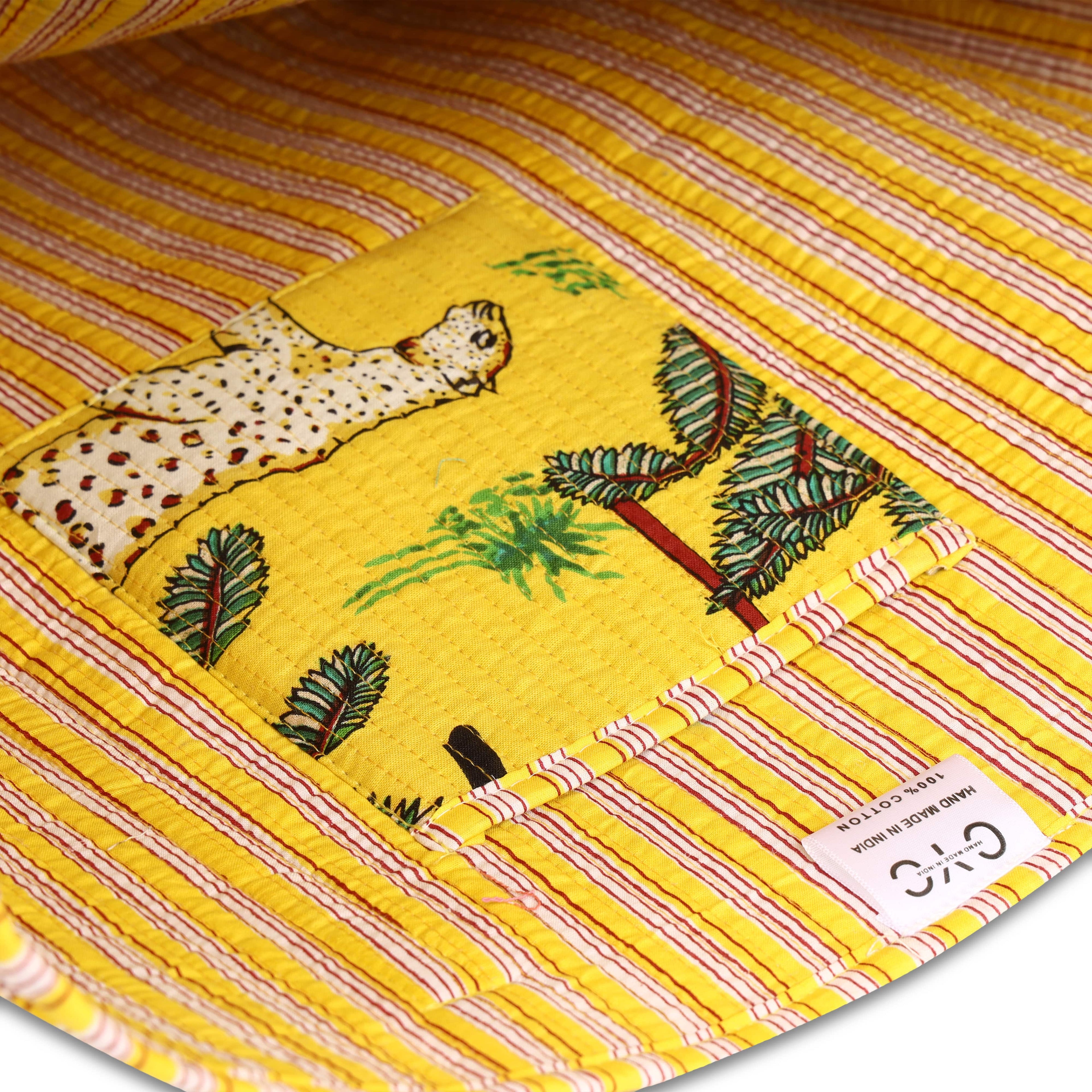 Detail of the hand-block-printed parrot and palm motif in saturated tropical colour on cream cotton