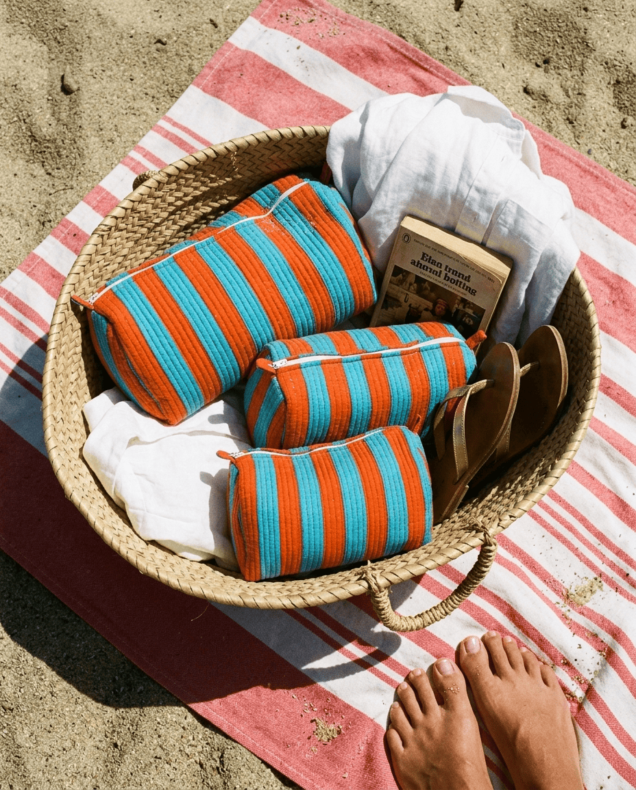 Woven straw beach basket with the Striped Cotton Travel Set in Orange and Blue tucked inside — handmade in Rajasthan by Conscious Yoga Collective