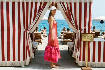 Woman holding the Love Suzani Velvet Tote in Hot Pink at a striped cabana entrance — handmade velvet tote from Conscious Yoga Collective