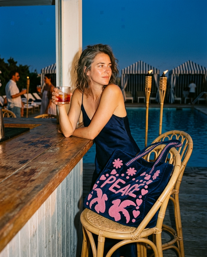 Sunset cocktail bar with the Peace Suzani Velvet Tote in Navy on the adjacent barstool — handmade in Rajasthan by Conscious Yoga Collective