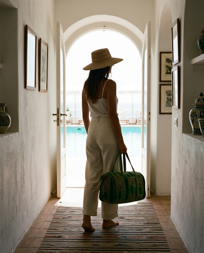 Woman in a whitewashed hallway carrying the Tibetan Tiger Velvet Weekender in Green — handmade in Rajasthan by Conscious Yoga Collective