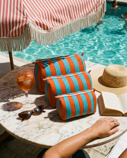 Marble poolside table under a striped cabana with the Striped Cotton Travel Set in Orange and Blue — handmade in Rajasthan by Conscious Yoga Collective