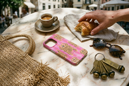 The Tibetan Tiger iPhone Case in Pink — overhead flat-lay on a sunlit Italian piazza marble cafe table beside an espresso