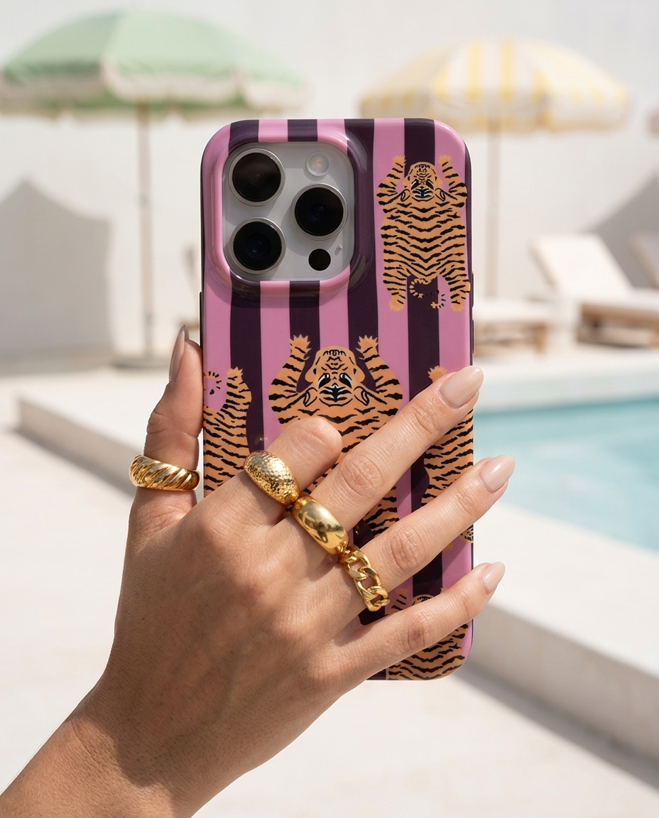 The Tibetan Tiger iPhone Case in Mauve Plum in a modern editorial poolside shot with pistachio parasols and chalk white concrete